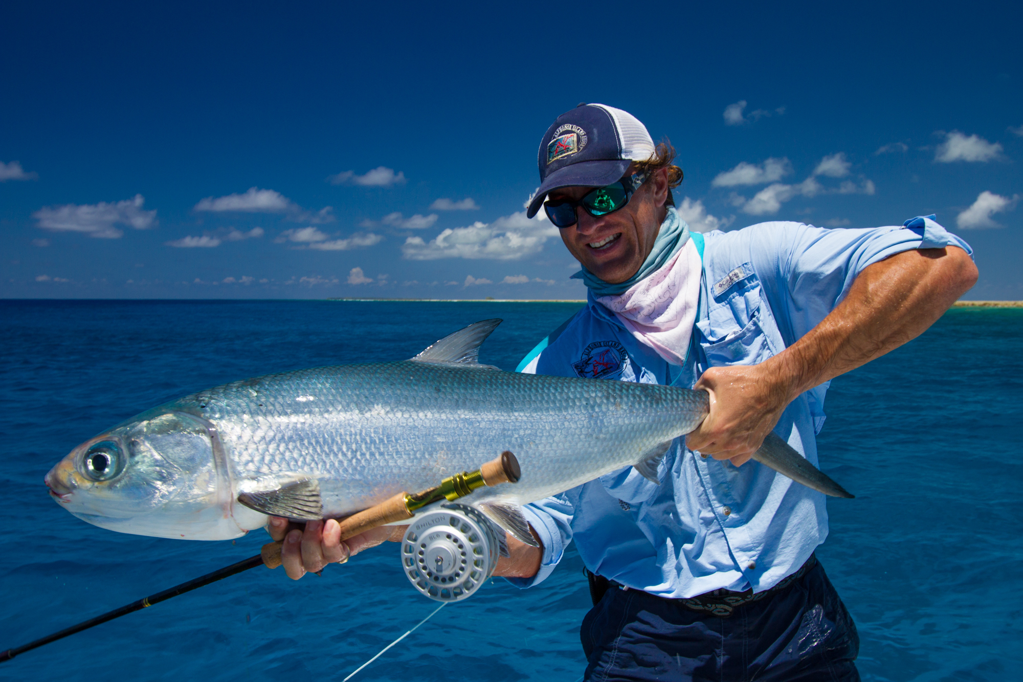 Happy fly fisherman proudly holding the milkfish caught on a fly.