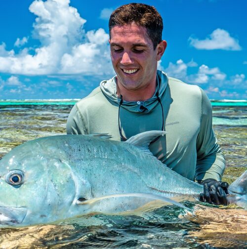 Happy fly fisherman with his bluefine trevally caught on a fly at Farquhar Atoll with Alphonse Fishing Co™
